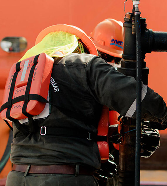 Colaboradores de Enermar con casco naranja y traje especial de seguridad, cargando de combustible a barco a través de auto-tanque