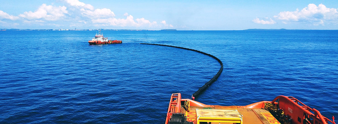 Barrera contra derrames (oil booms), producto de Enermar, siendo colocada en alta mar por barcaza