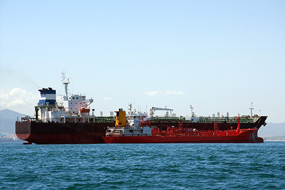 Suministro de combustible por barcazas de Enermar, realizado entre dos barcos rojos en el mar